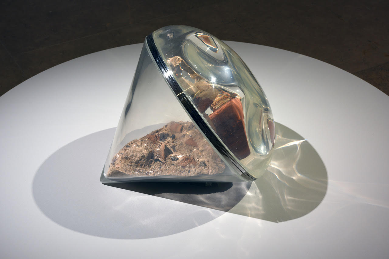 Blow Up, a sculptural artwork with a transparent curved form and mineral elements