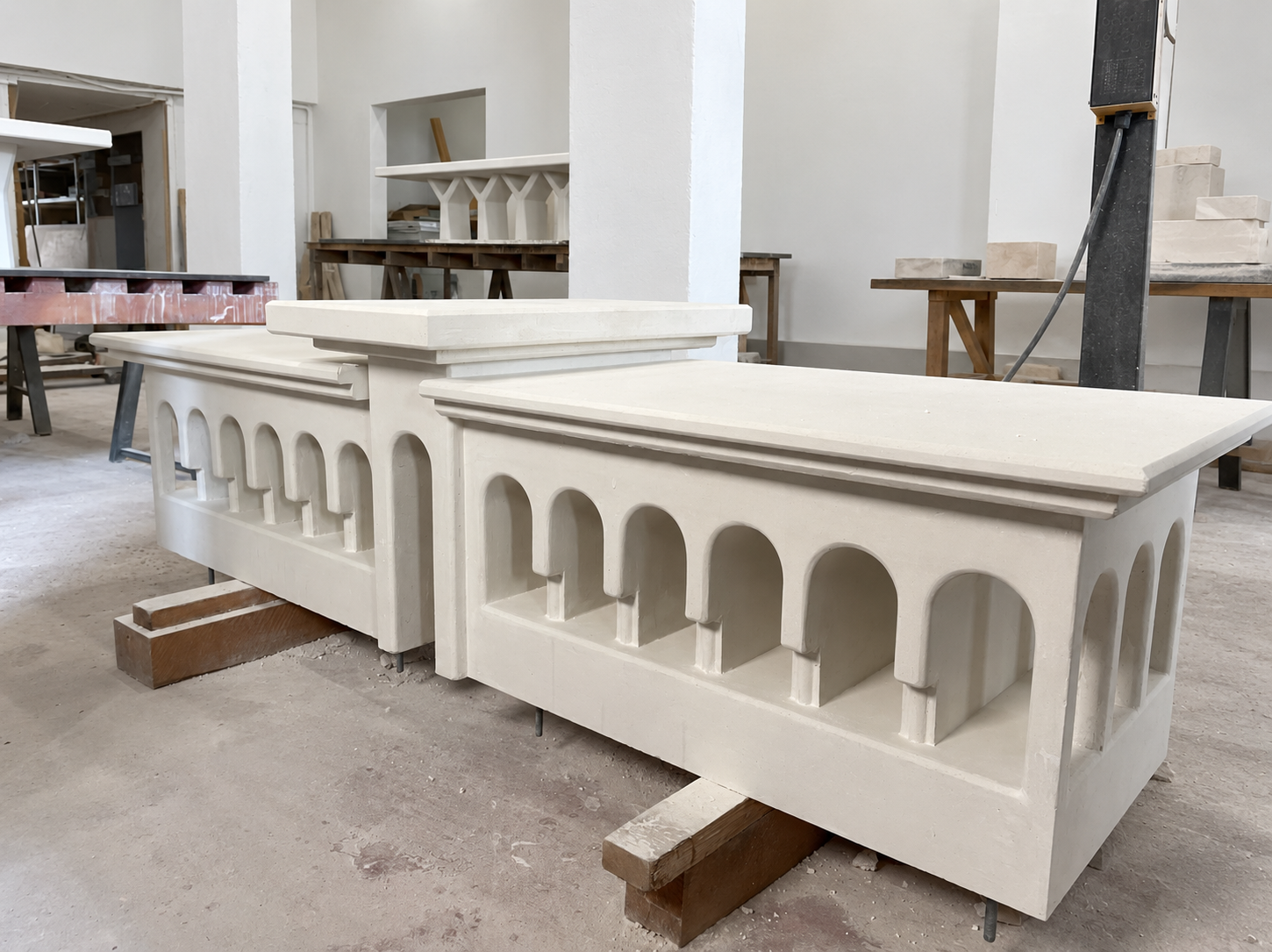 White architectural concrete bench with repeating arches in a workshop